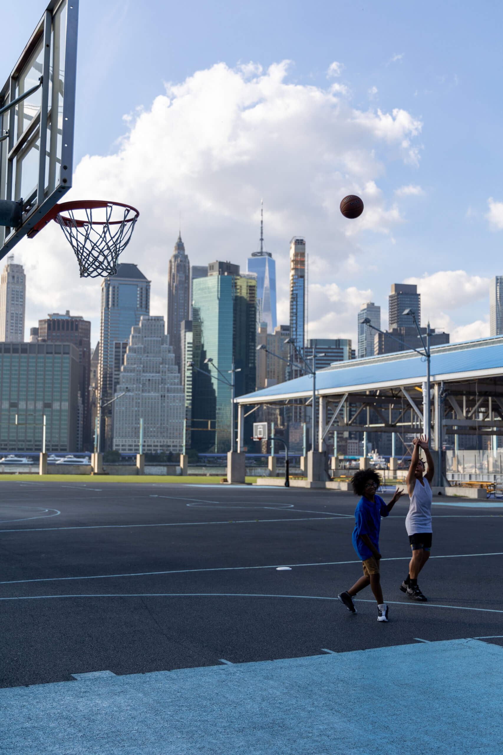 A photo of two teenagers playing basketball against each other on the outdoor courts in Brooklyn, capturing the energy and urban spirit of the game.