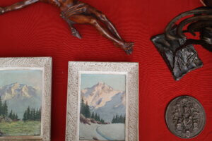 A photo from the Annecy flea market featuring two framed mountain photos, a statue of Christ’s body with visible feet, a rooster statue, and a medal