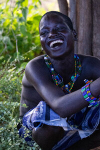 A photo of a Hamar individual laughing joyfully during the bull-jumping ceremony in Ethiopia, reflecting the cultural vibrancy of the event