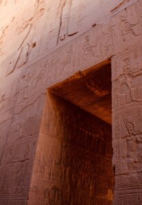 The gate of Kom Ombo Temple in Egypt, adorned with hieroglyphics, illuminated by a beautiful sunset.