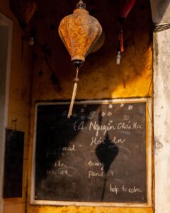 A traditional lantern in Hoi An, Vietnam, casting intricate shadows of silhouettes on a wall during sunset