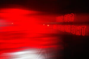 A blurred red neon sign at the Rodeo Bar in Dallas, Texas, reflecting the phrase "God Save Rodeo Bar" backward
