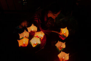 A woman in Hoi An, Vietnam, selling glowing candles at night, creating a serene and mystical atmosphere