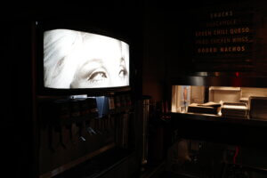 A drink dispenser at the Rodeo Bar in Dallas featuring an image of a woman’s gaze directed toward the bar menu, playfully hinting at an appetite for nachos