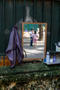 A street mirror in Hanoi, Vietnam, reflecting the candid moment of a boy and girl in school uniforms engaged in conversation.